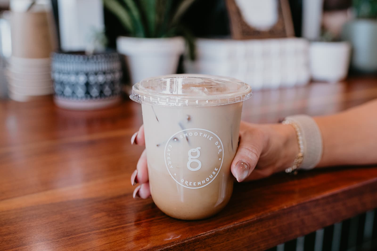 An iced Greenhouse drink held at the walnut bar counter