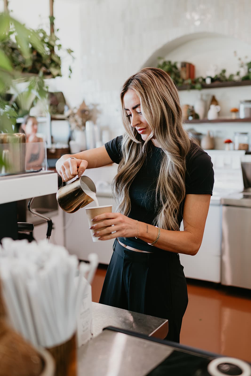 Pouring steamed milk into a Greenhouse cup behind the counter